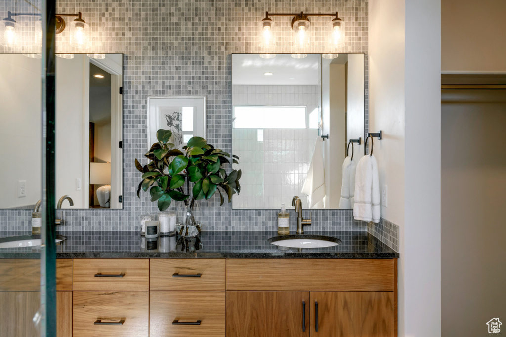 Bathroom featuring double vanity and backsplash