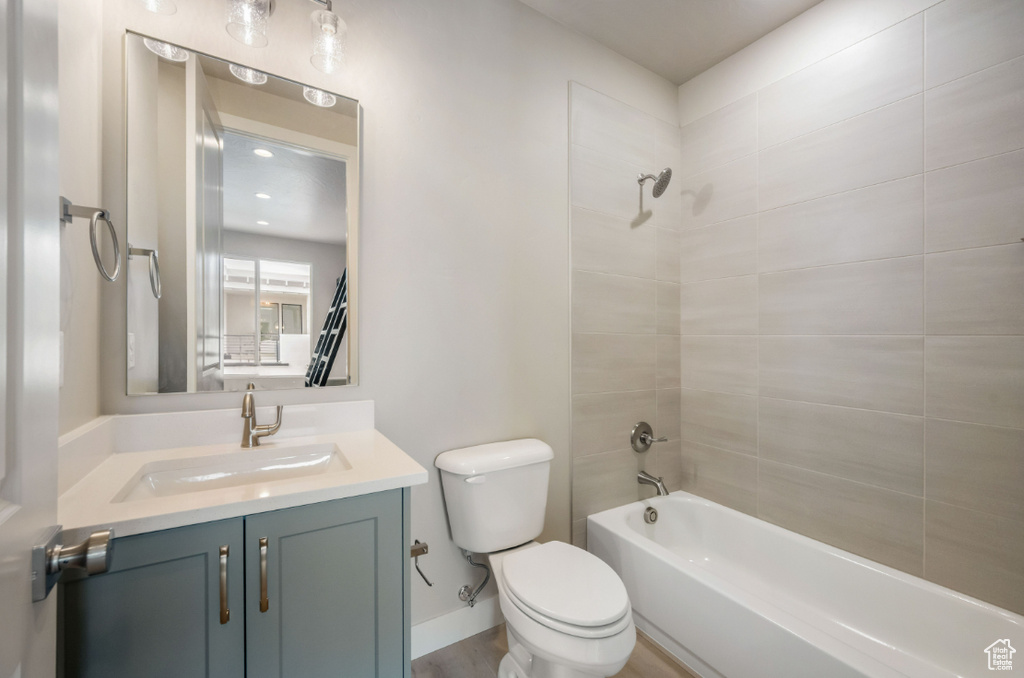 Bathroom with vanity, toilet, bathtub / shower combination, and baseboards