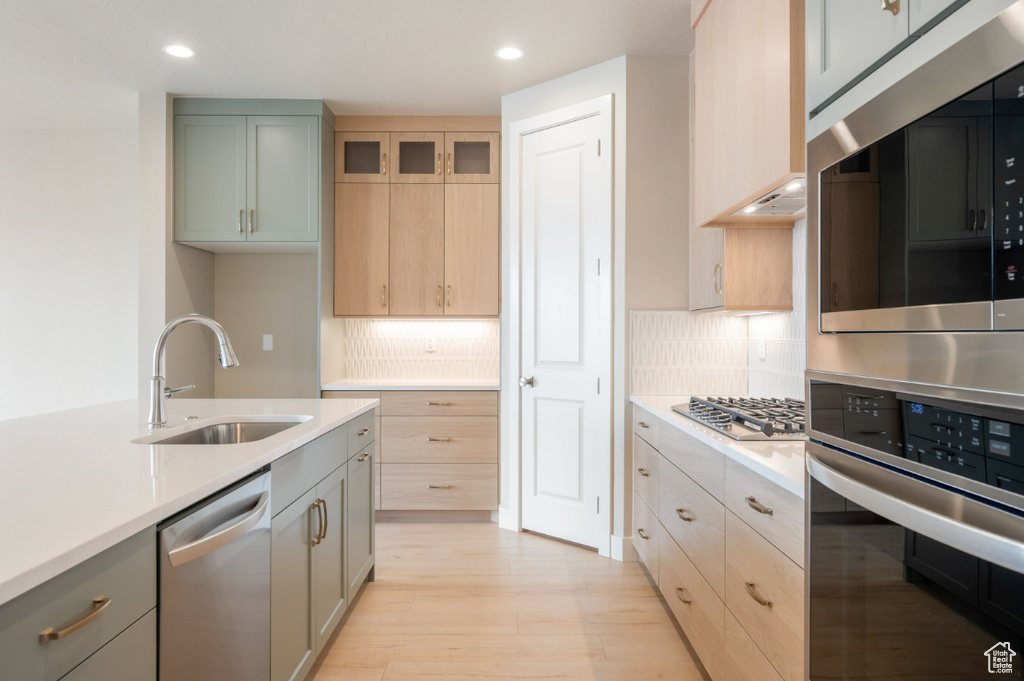 Kitchen featuring stainless steel appliances, a sink, light countertops, light wood finished floors, and recessed lighting