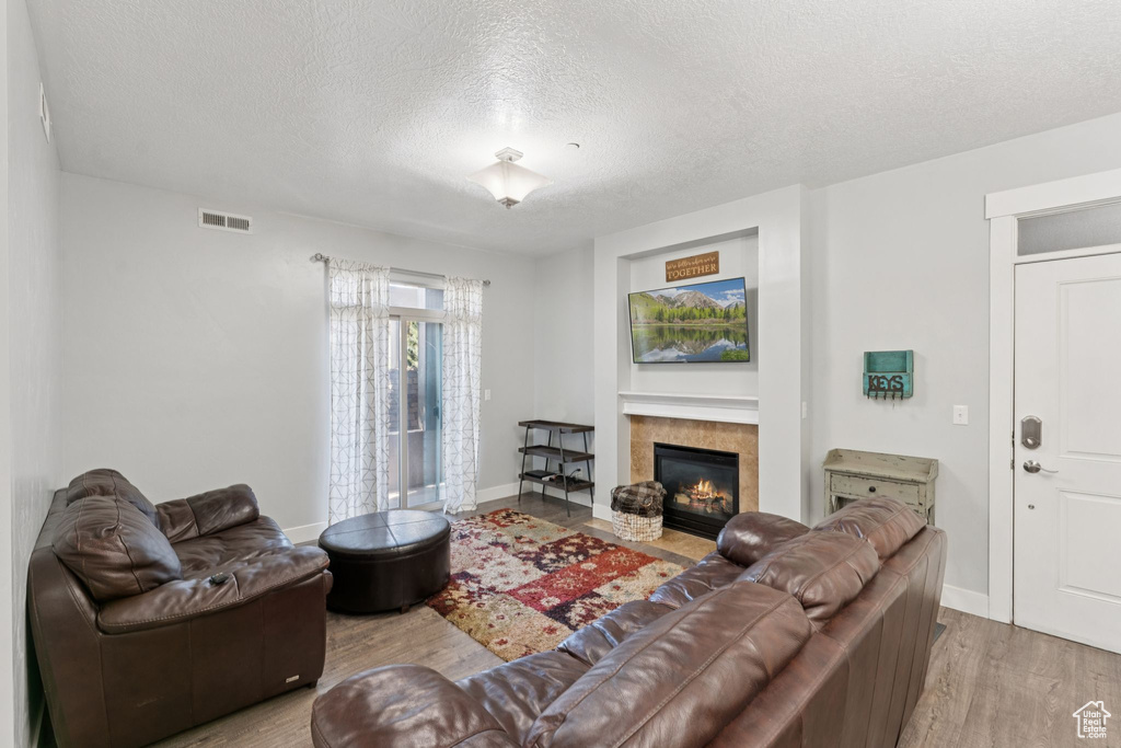 Living area featuring wood finished floors, a textured ceiling, a fireplace, and baseboards