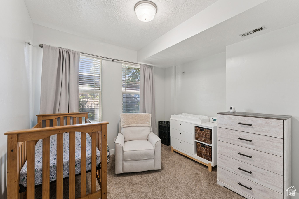 Bedroom featuring light colored carpet and a crib
