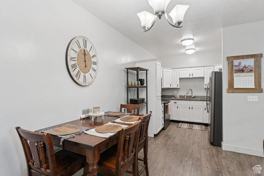 Dining space with a chandelier, wood finished floors, and baseboards