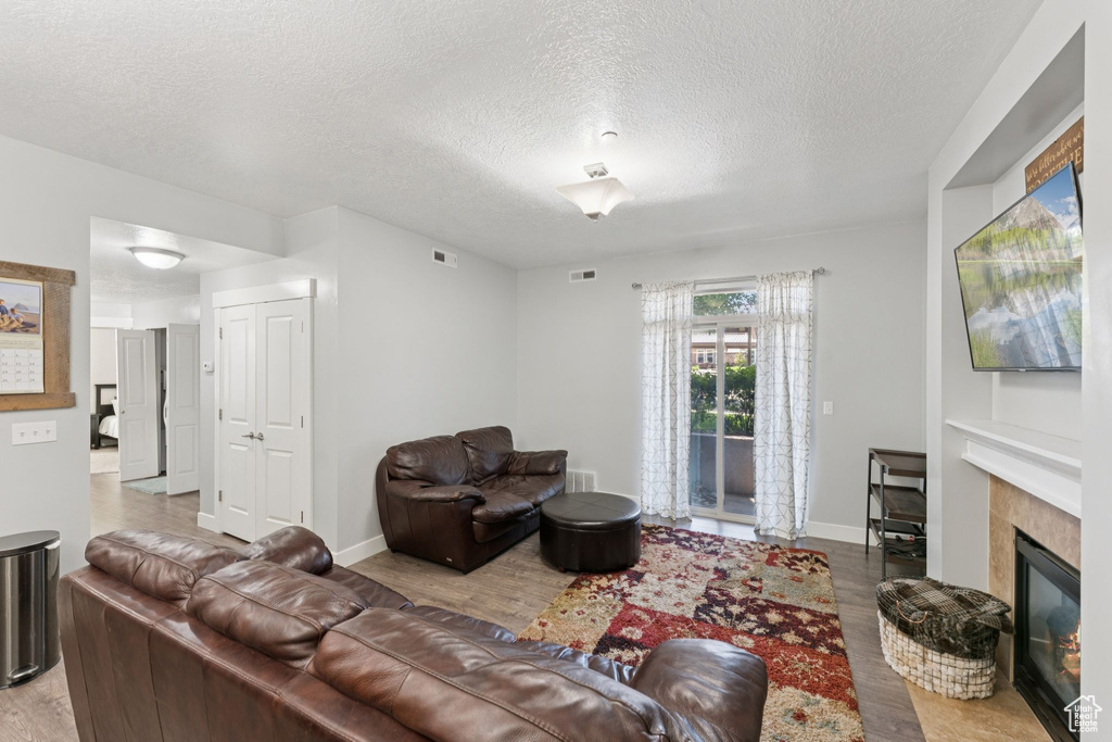 Living area with wood finished floors, a textured ceiling, a fireplace, and baseboards