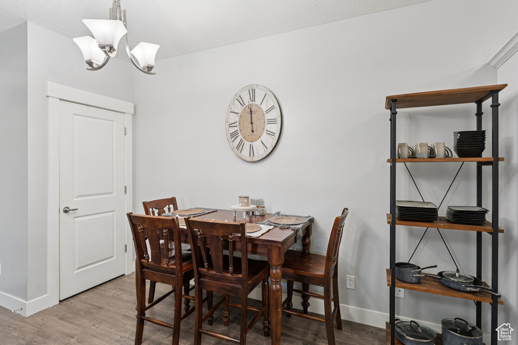 Dining room with wood finished floors, a chandelier, and baseboards