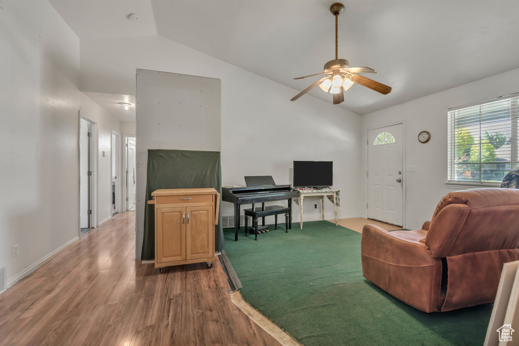 Living room with vaulted ceiling, wood finished floors, and a ceiling fan