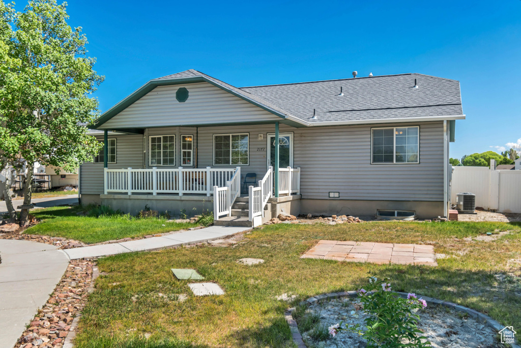 Bungalow-style home with covered porch, roof with shingles, and central AC unit