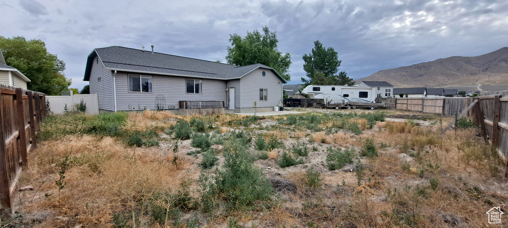 Rear view of house with a fenced backyard and a mountain view