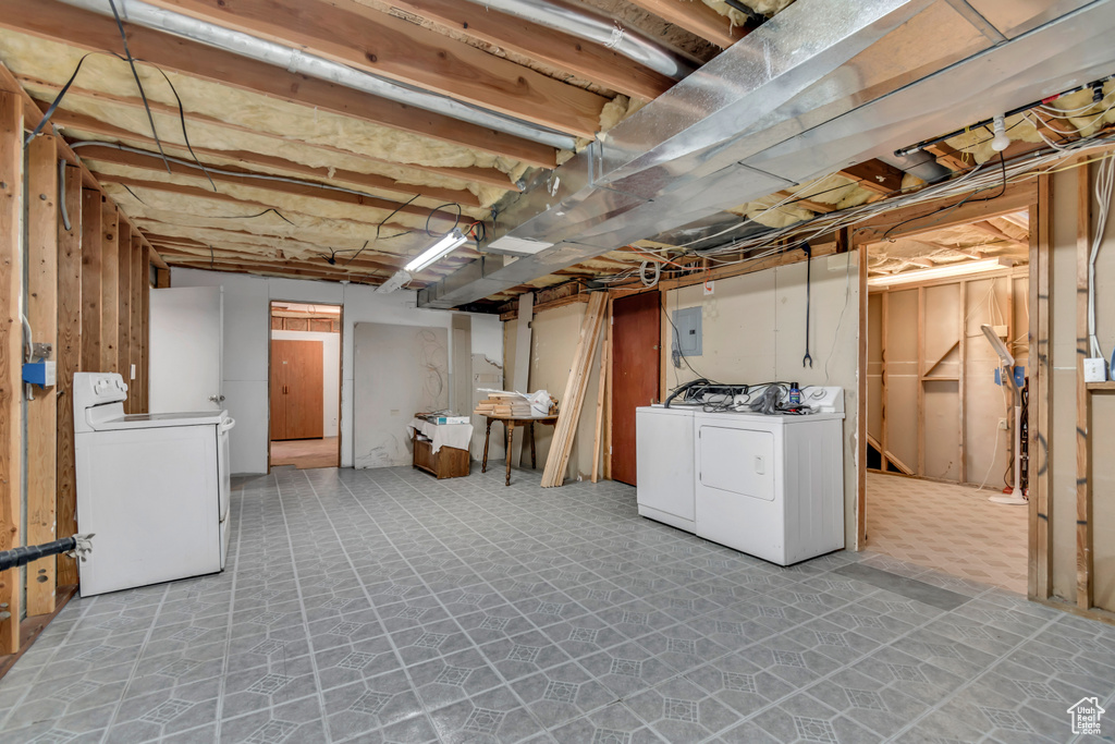 Unfinished below grade area featuring washing machine and dryer and electric panel