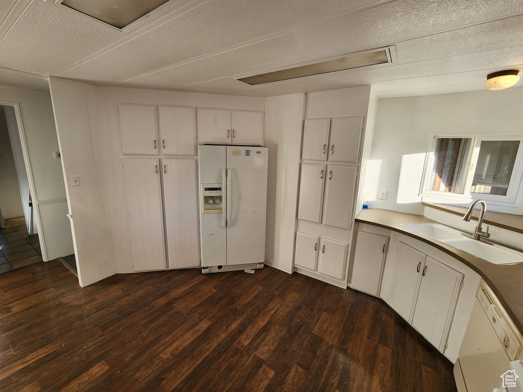 Kitchen with white appliances, a sink, dark wood-style flooring, white cabinets, and light countertops