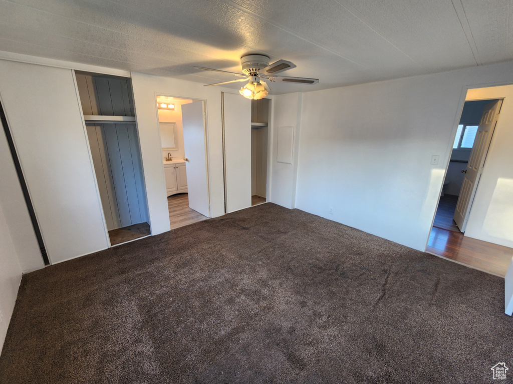 Unfurnished bedroom featuring carpet floors, connected bathroom, a sink, and ceiling fan