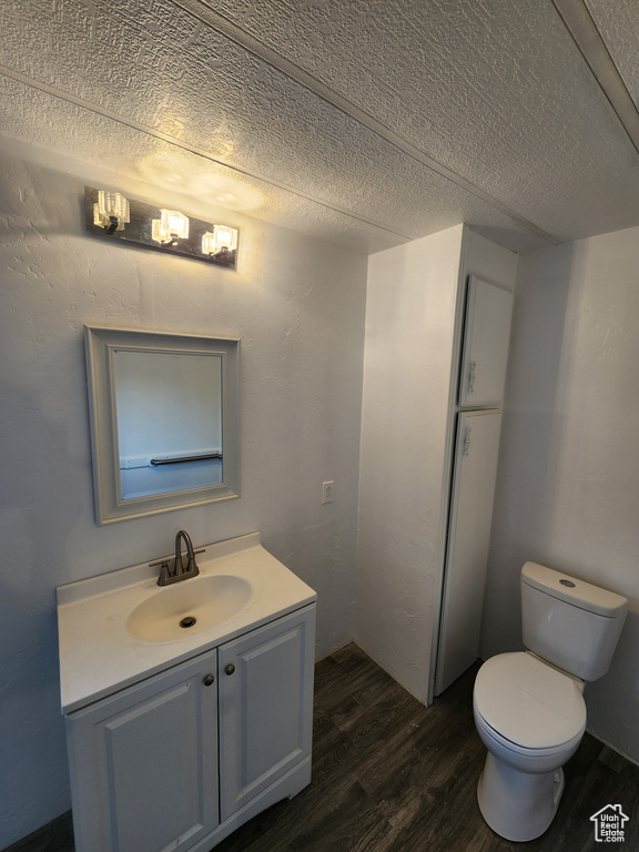 Bathroom featuring wood finished floors, vanity, toilet, and a textured ceiling