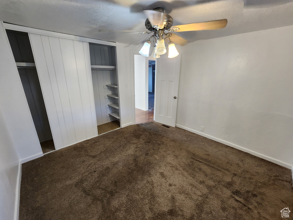 Unfurnished bedroom with carpet, a closet, baseboards, and a ceiling fan
