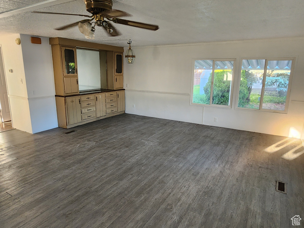 Unfurnished living room featuring dark wood-style floors, a ceiling fan, and a textured ceiling