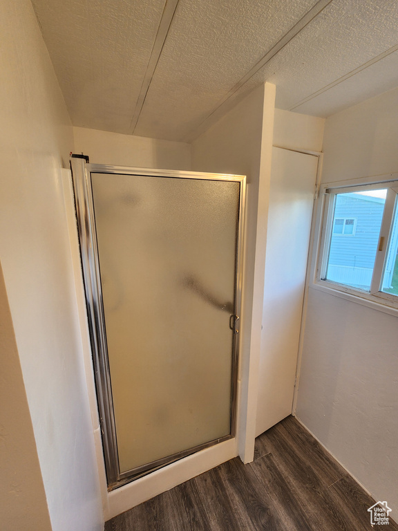 Full bath featuring wood finished floors, a stall shower, and a textured ceiling