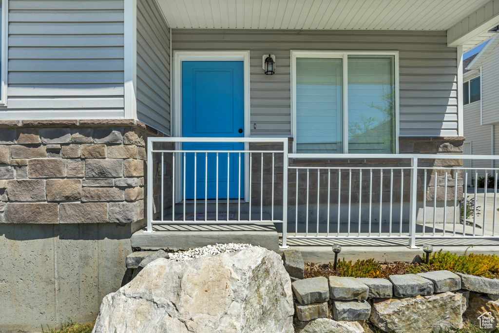 Doorway to property with covered porch and stone siding