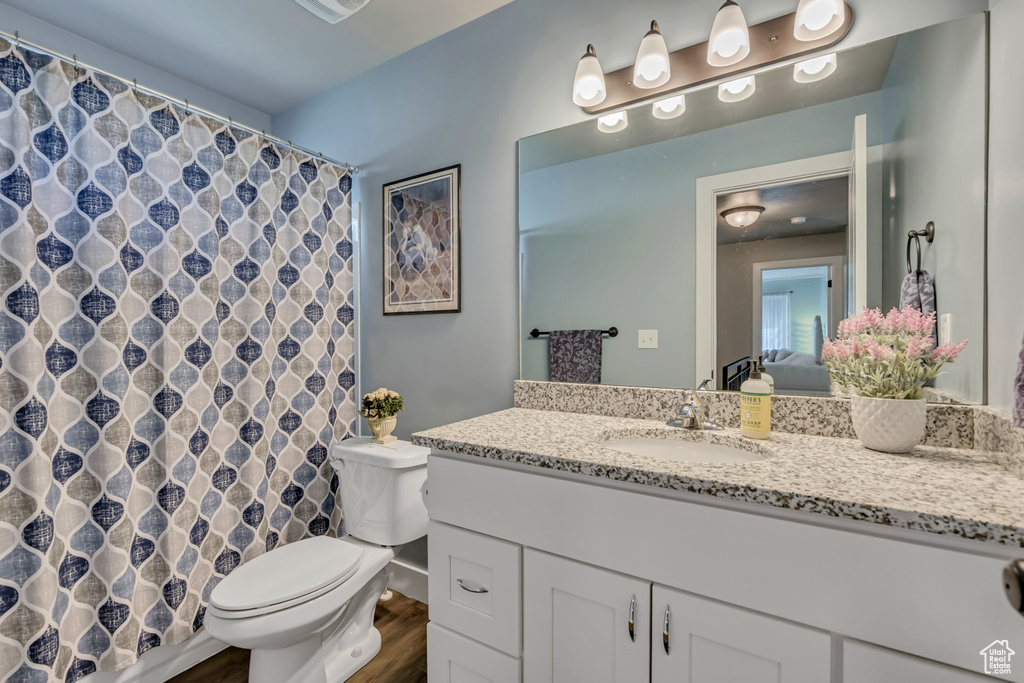Bathroom with toilet, vanity, wood finished floors, connected bathroom, and curtained shower