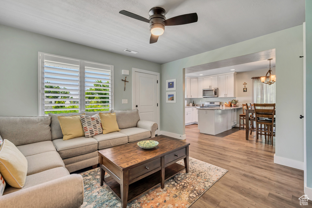 Living area with a ceiling fan, a chandelier, healthy amount of natural light, and light wood-style floors