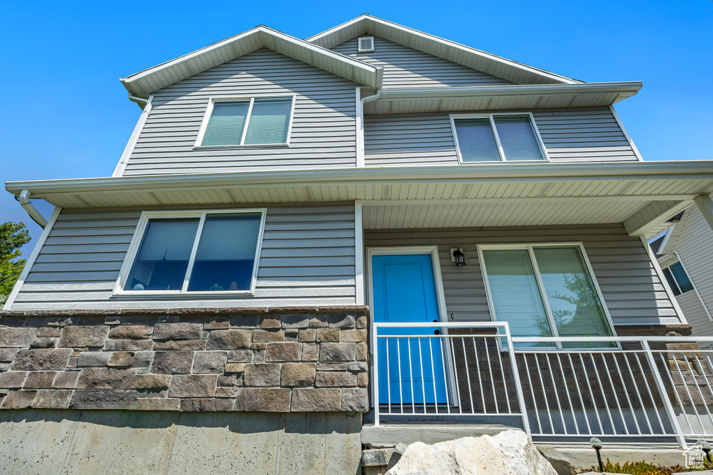 View of front facade featuring covered porch and stone siding