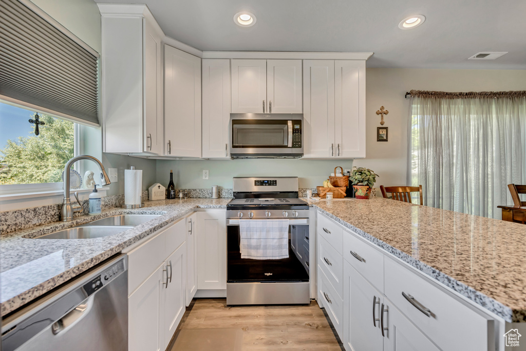 Kitchen featuring stainless steel appliances, a sink, recessed lighting, white cabinetry, and light wood finished floors