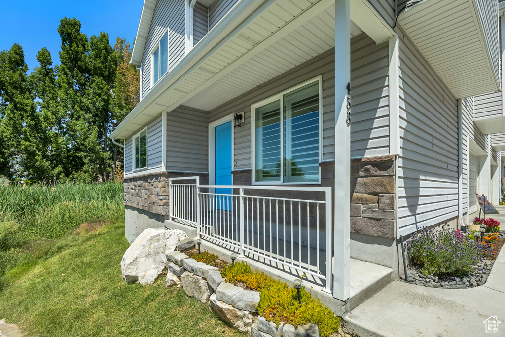 View of side of property with stone siding and covered porch
