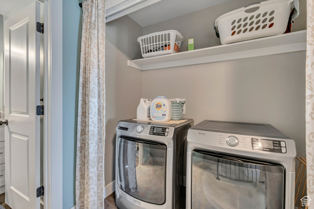 Washroom with washing machine and clothes dryer and wood finished floors
