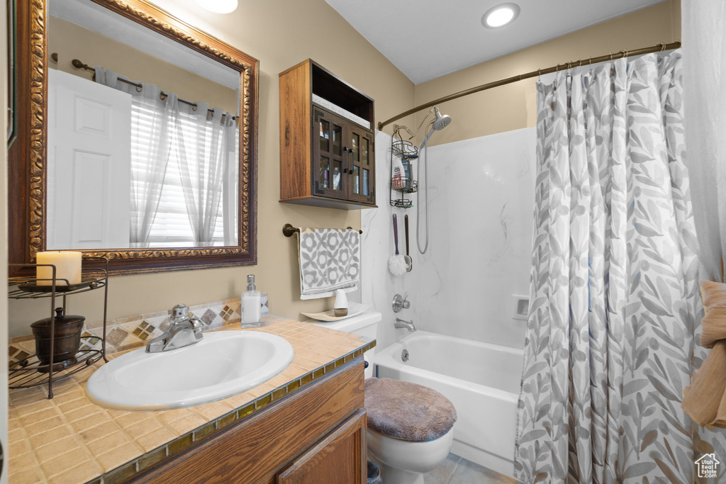 Full bathroom with toilet, vanity, and shower / tub combo with curtain