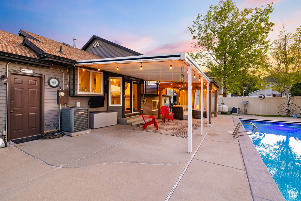 Pool at dusk with a patio area and cooling unit