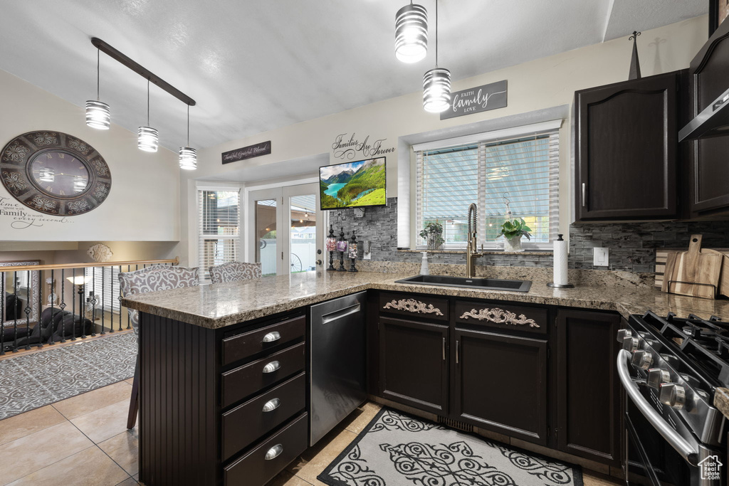 Kitchen featuring stainless steel appliances, a sink, dark cabinets, tasteful backsplash, and lofted ceiling