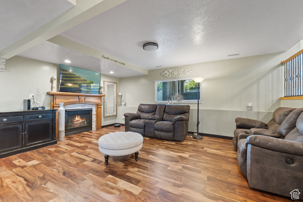 Living room with wood finished floors, baseboards, a glass covered fireplace, and recessed lighting