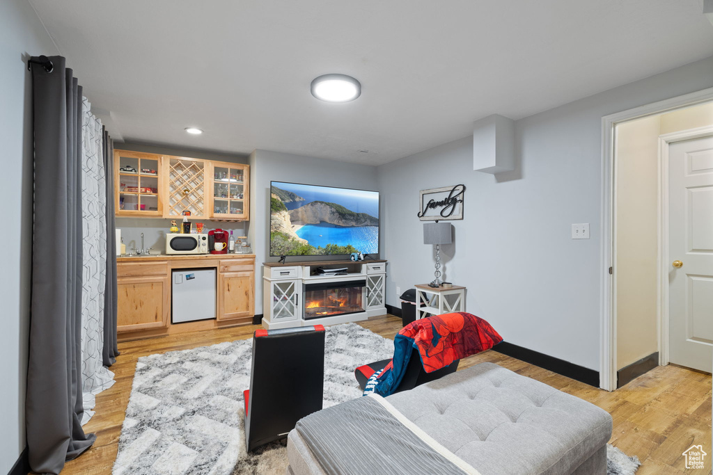 Living area featuring wet bar, light wood finished floors, baseboards, and recessed lighting