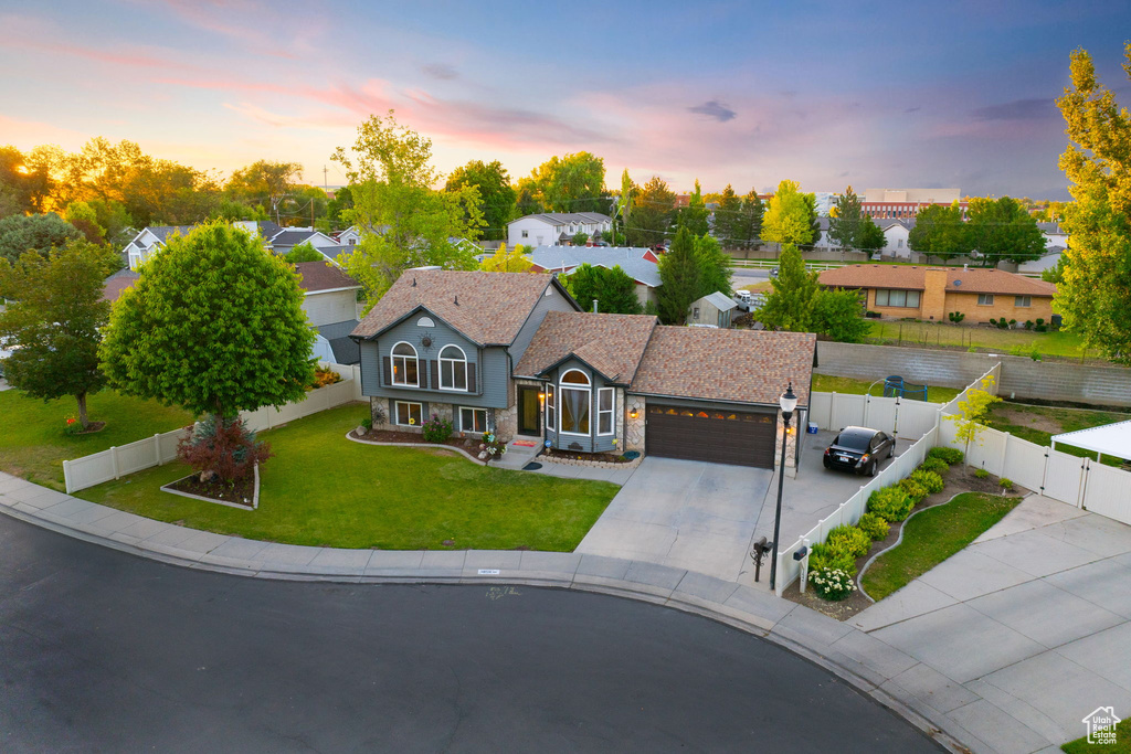 View of front of home with a gate, an attached garage, stone siding, and driveway