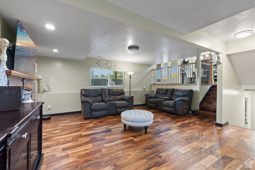 Living area with a textured ceiling, wood finished floors, stairway, baseboards, and a fireplace