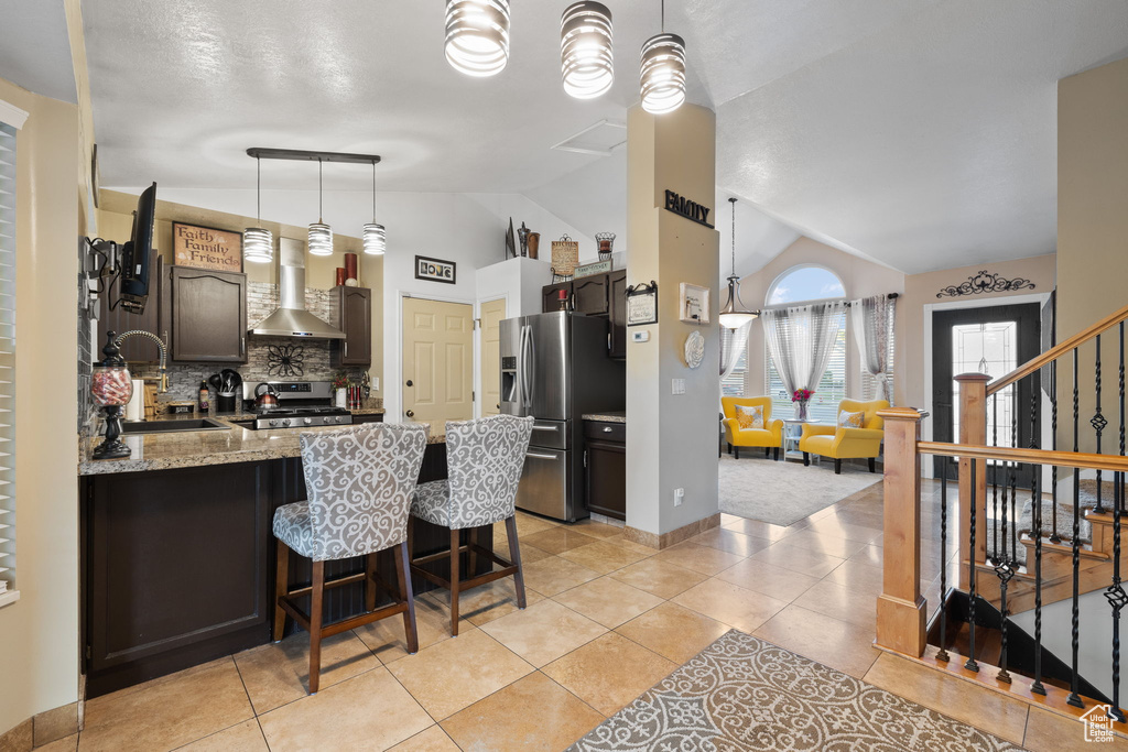 Kitchen with appliances with stainless steel finishes, a sink, a peninsula, decorative backsplash, and wall chimney range hood