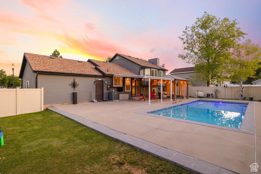 Pool at dusk featuring a patio area and cooling unit