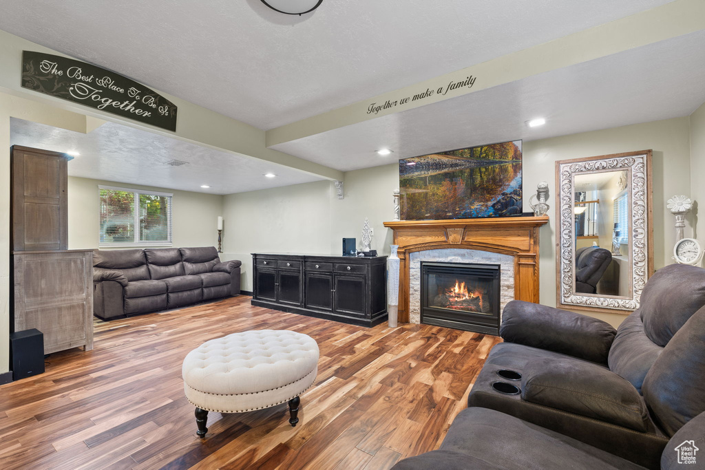 Living room with wood finished floors, a fireplace, and recessed lighting