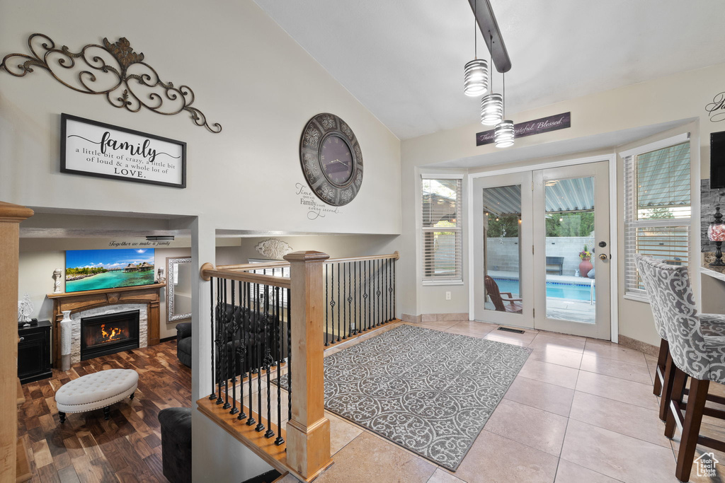 Foyer featuring a warm lit fireplace, baseboards, high vaulted ceiling, and tile patterned flooring