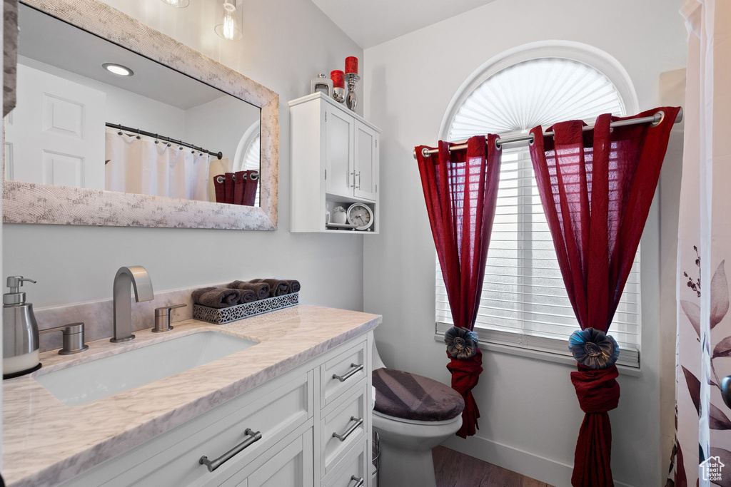 Bathroom featuring vanity, toilet, wood finished floors, and baseboards