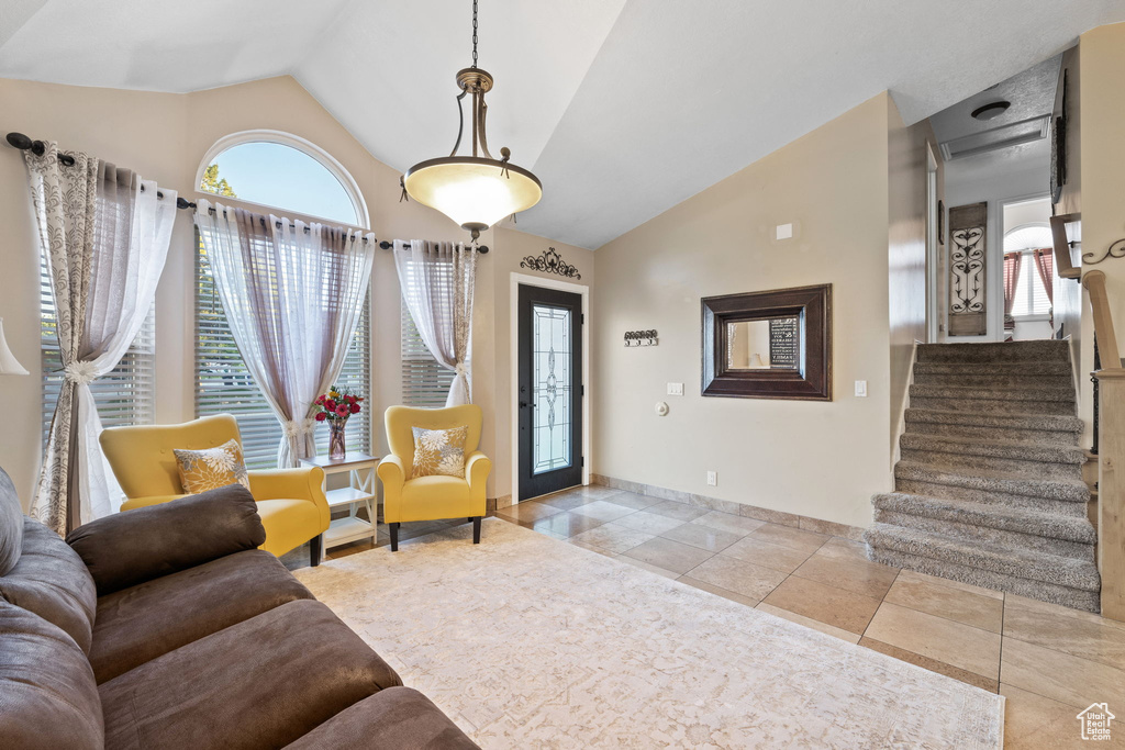 Entrance foyer featuring stairs, baseboards, high vaulted ceiling, and light tile patterned flooring