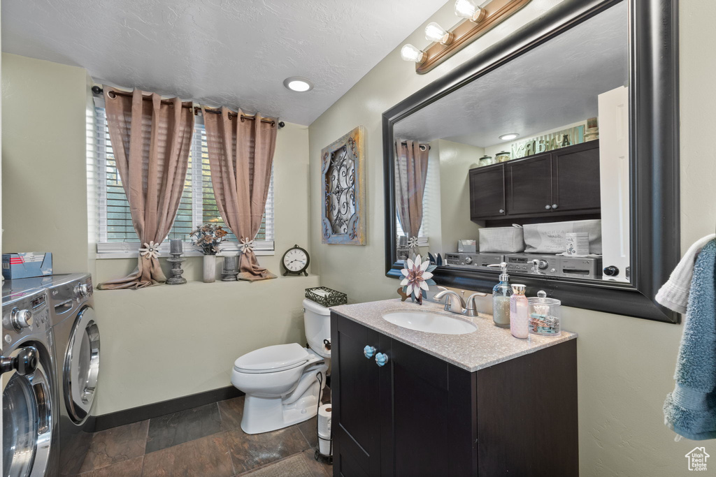 Bathroom with separate washer and dryer, vanity, toilet, and baseboards
