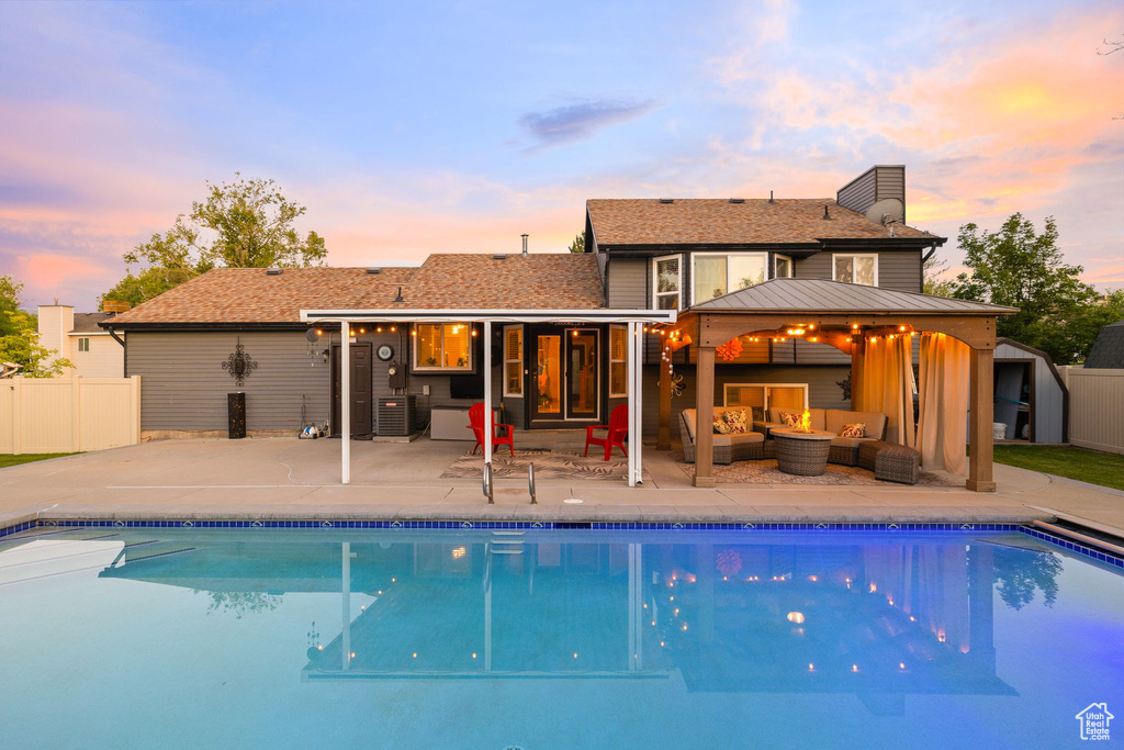 Back of house at dusk featuring an outdoor living space, a patio area, a gazebo, a chimney, and a standing seam roof