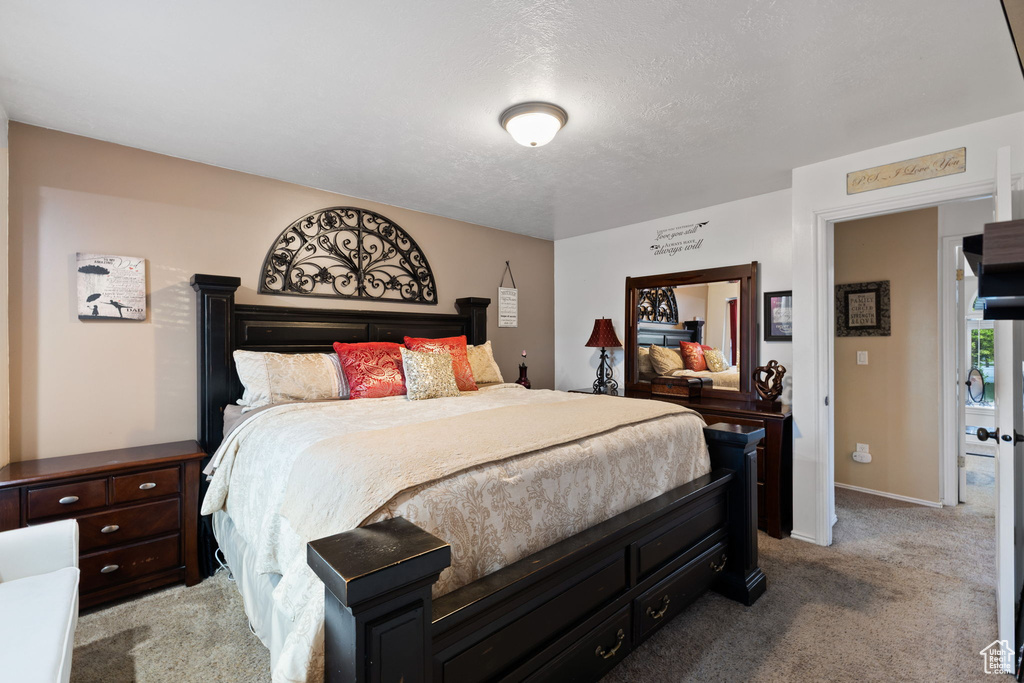Bedroom featuring light carpet, a textured ceiling, and baseboards