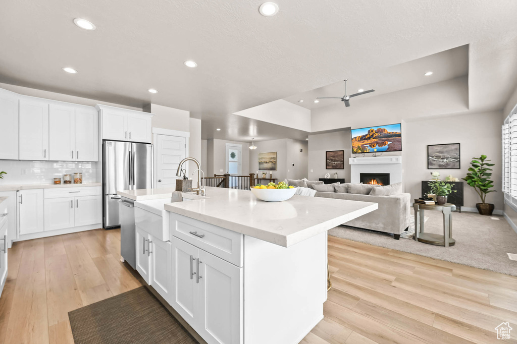 Kitchen with a sink, a raised ceiling, appliances with stainless steel finishes, recessed lighting, and a warm lit fireplace