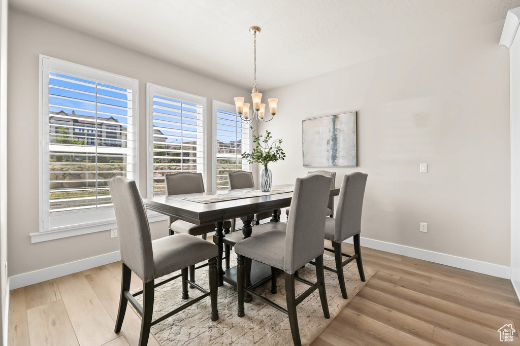 Dining area featuring a chandelier, baseboards, plenty of natural light, and light wood-style floors