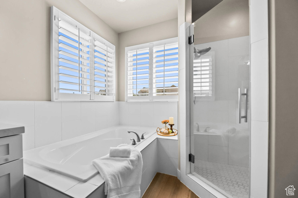 Full bathroom featuring a stall shower, a bath, and wood finished floors