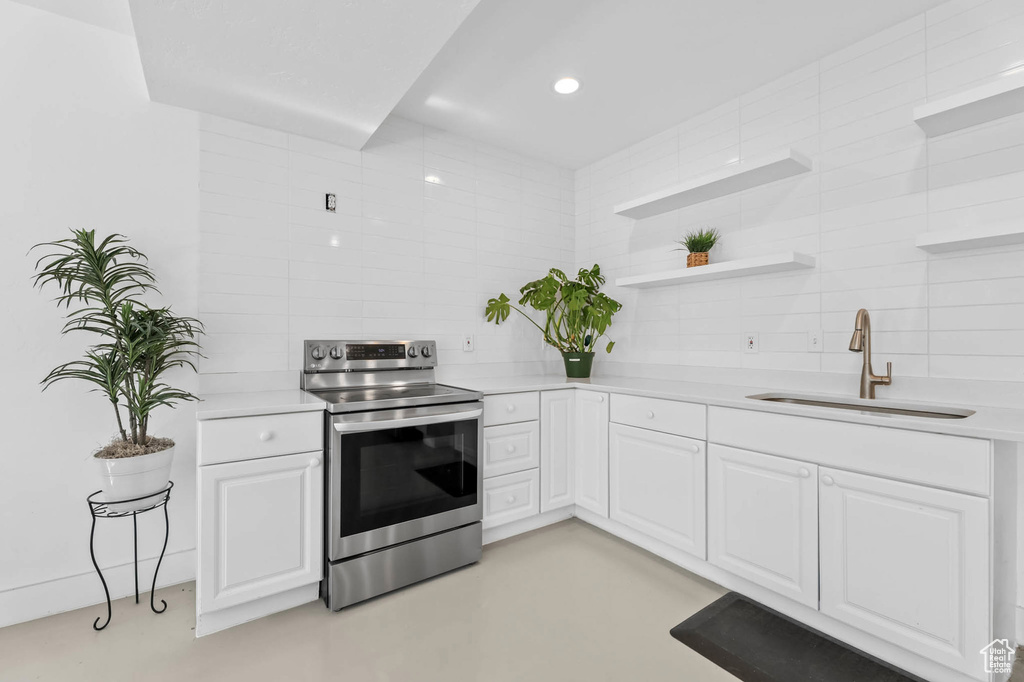 Kitchen featuring electric stove, a sink, tasteful backsplash, light countertops, and recessed lighting