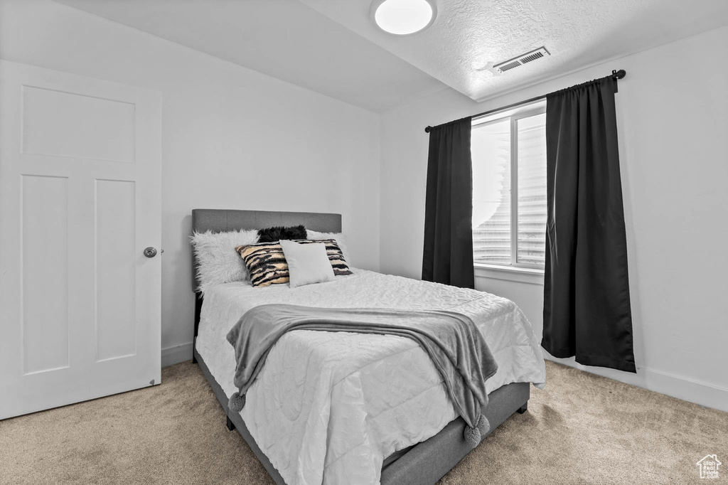 Carpeted bedroom featuring a textured ceiling and baseboards