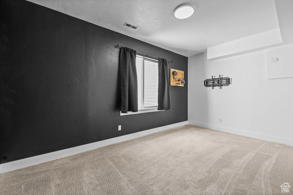 Empty room with carpet floors, baseboards, and a textured ceiling