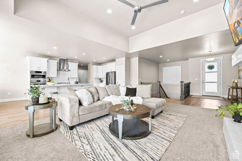 Living area featuring baseboards, ceiling fan, recessed lighting, and light wood-style flooring