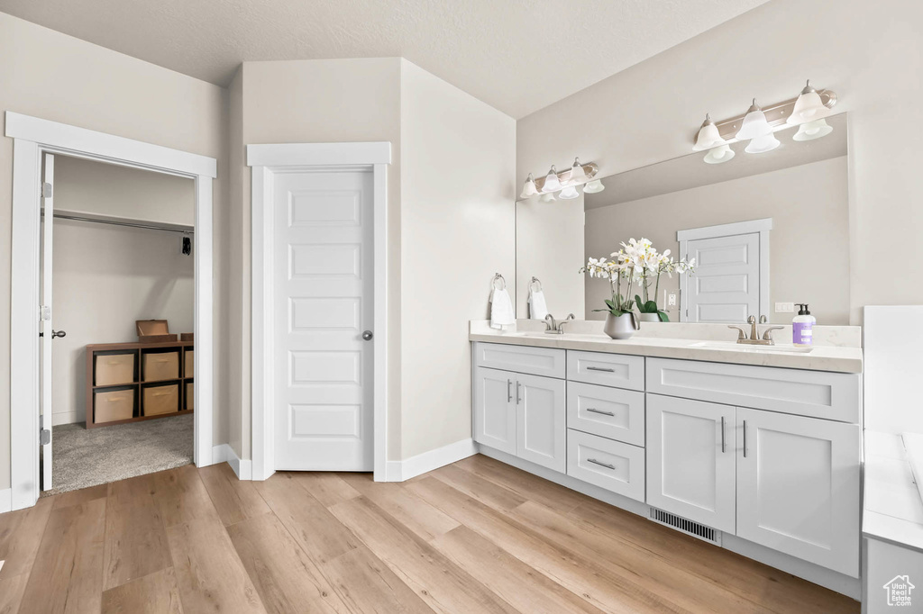 Bathroom featuring double vanity, wood finished floors, and baseboards