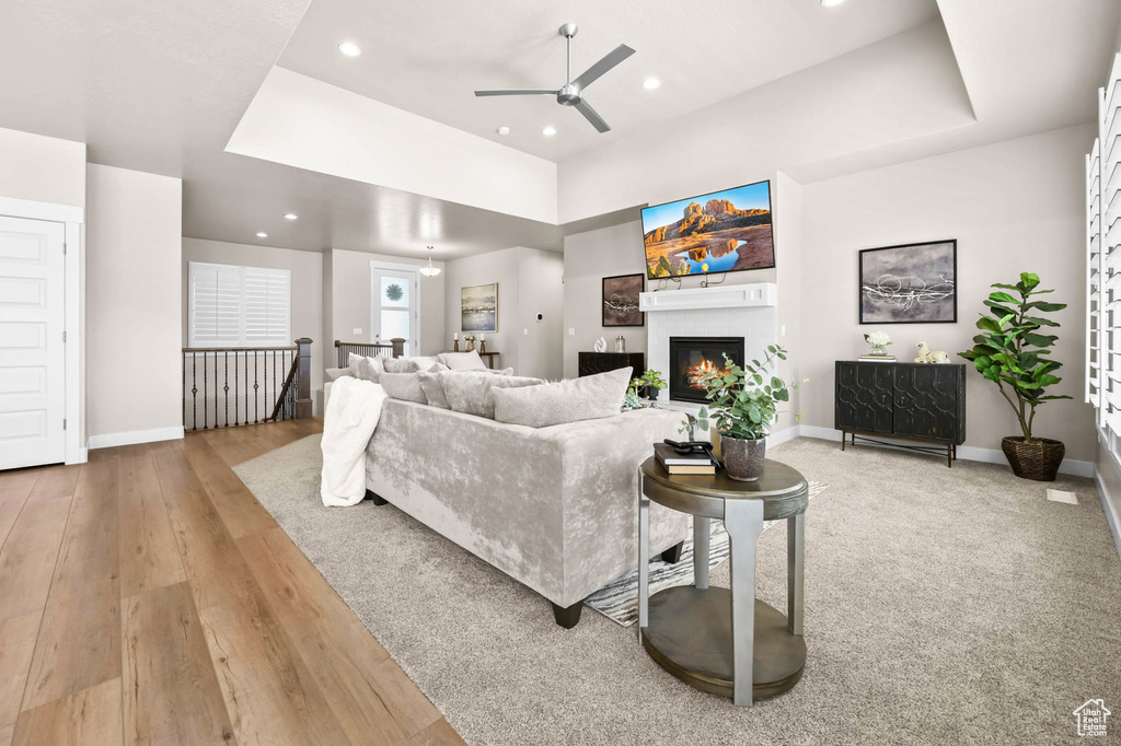 Living area featuring a ceiling fan, baseboards, recessed lighting, a glass covered fireplace, and a tray ceiling